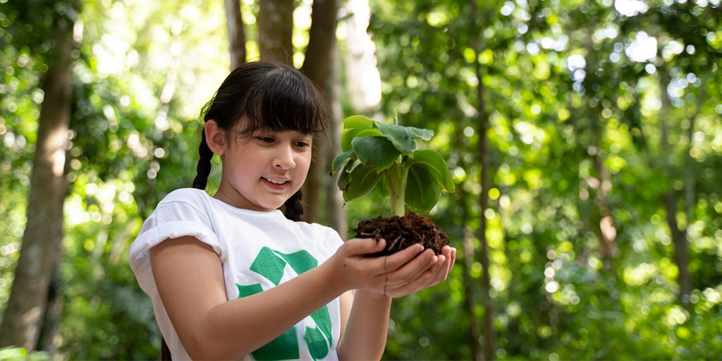 a young girl holds a plant in the forest