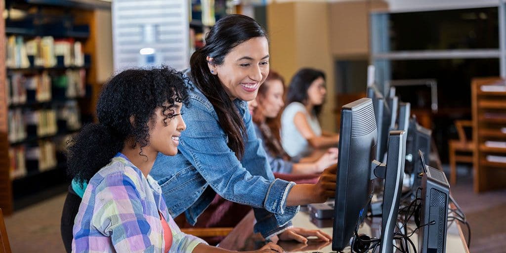 a woman helps a student on the computer