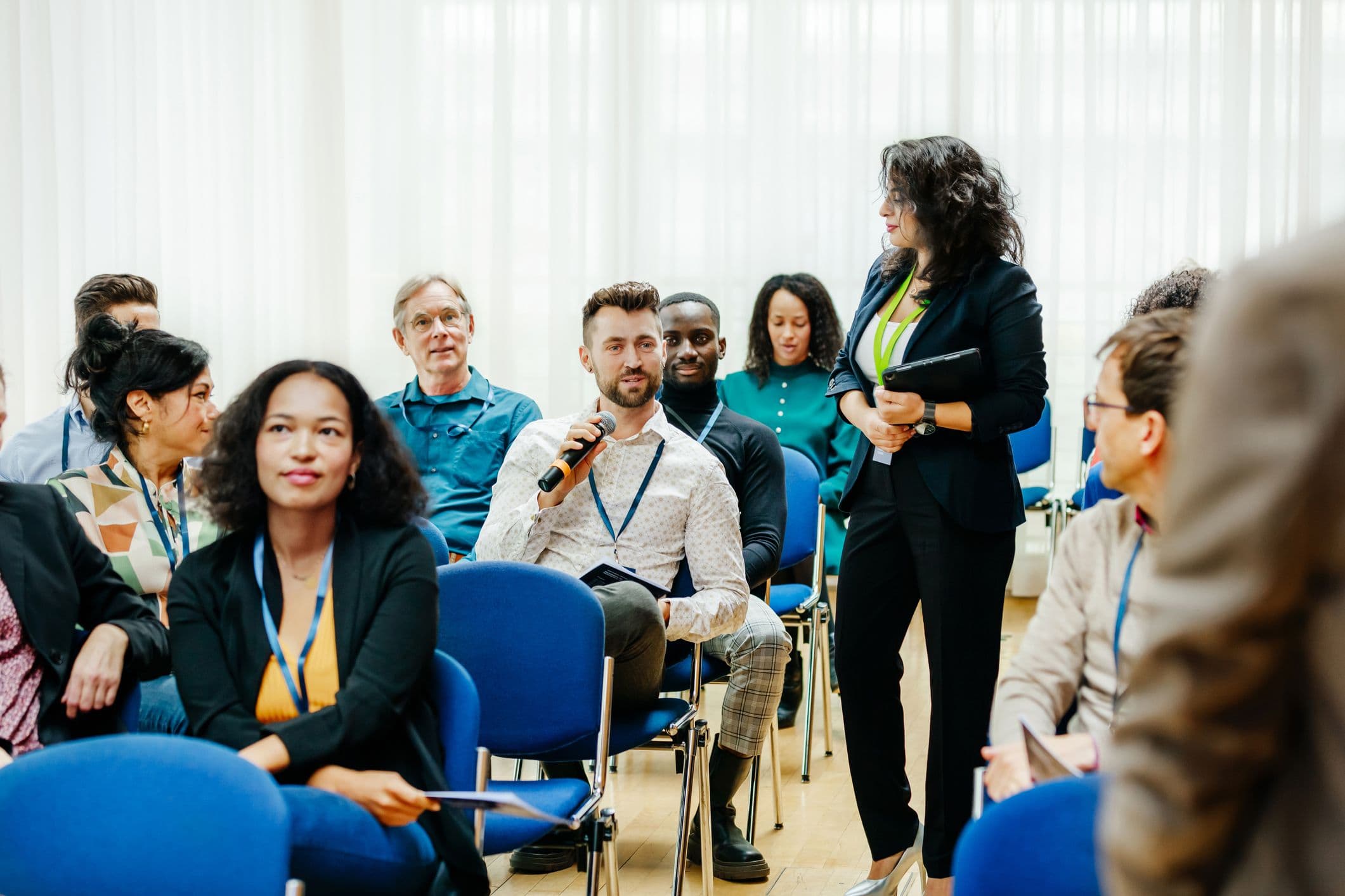 A conference attendee using a microphone to ask a question to the speaker during a business presentation.