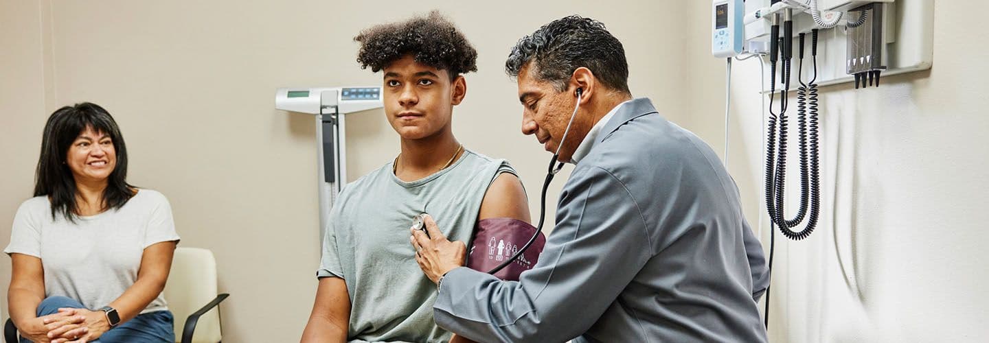a doctor uses a stethoscope to listen to a young man patient