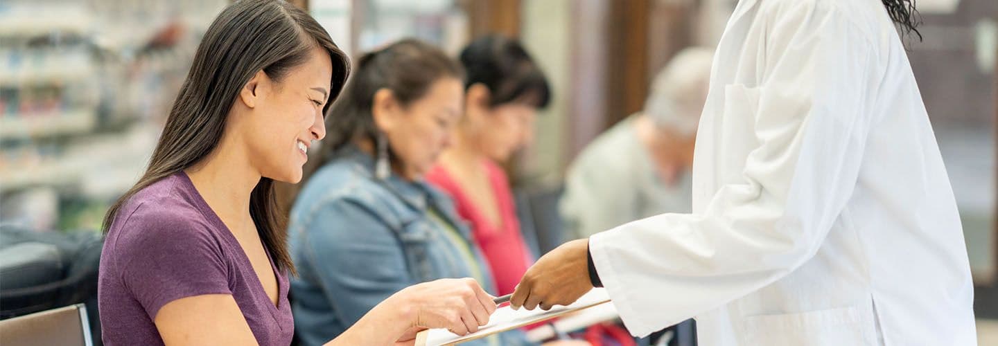 a young woman fills out forms at a doctor's office