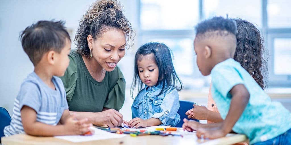 a teacher draws with her young students