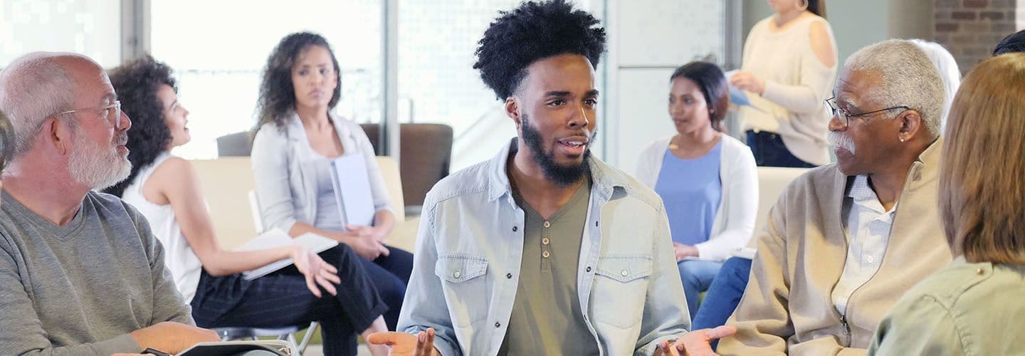 a young man speaks in a group setting