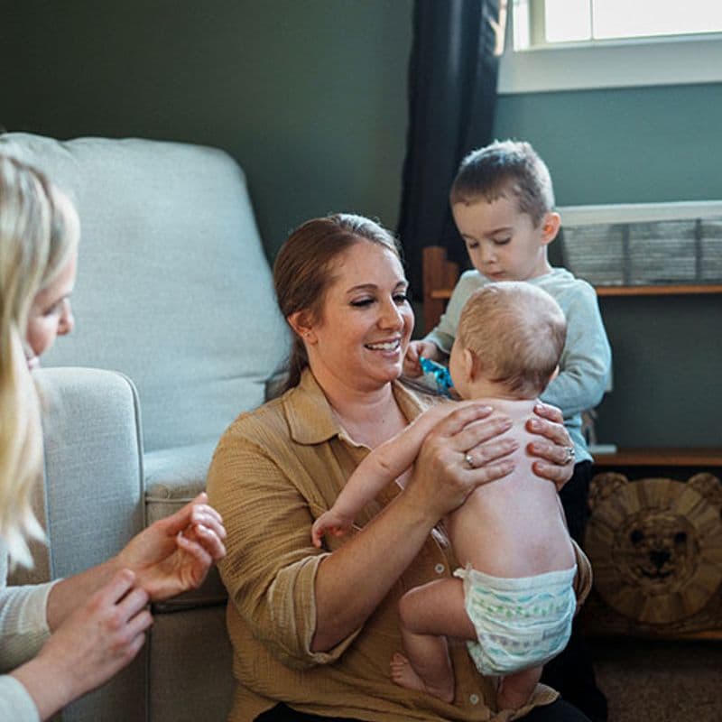 a nurse helps a mother with a young baby