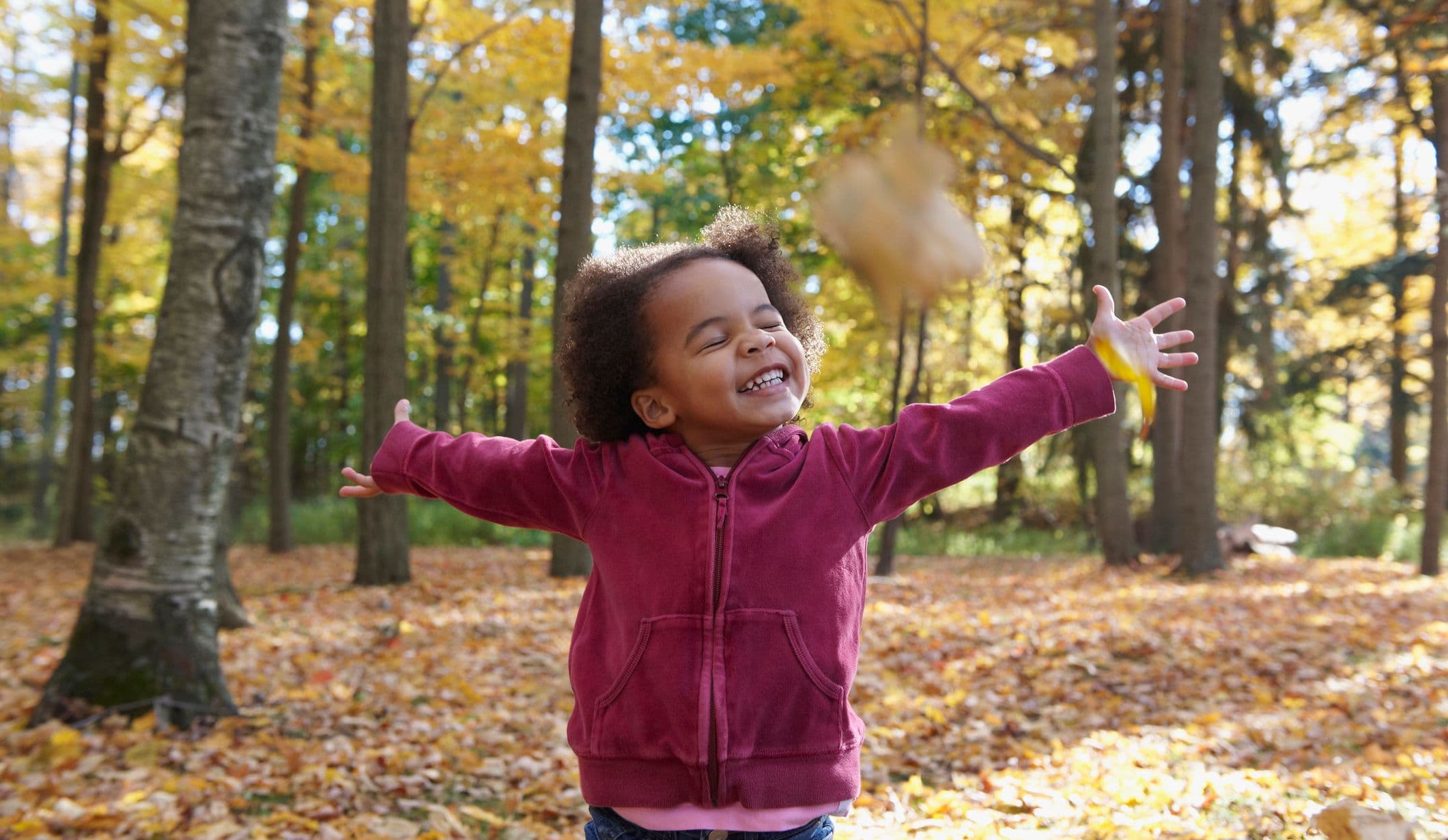 African American girl playing in autumn leaves