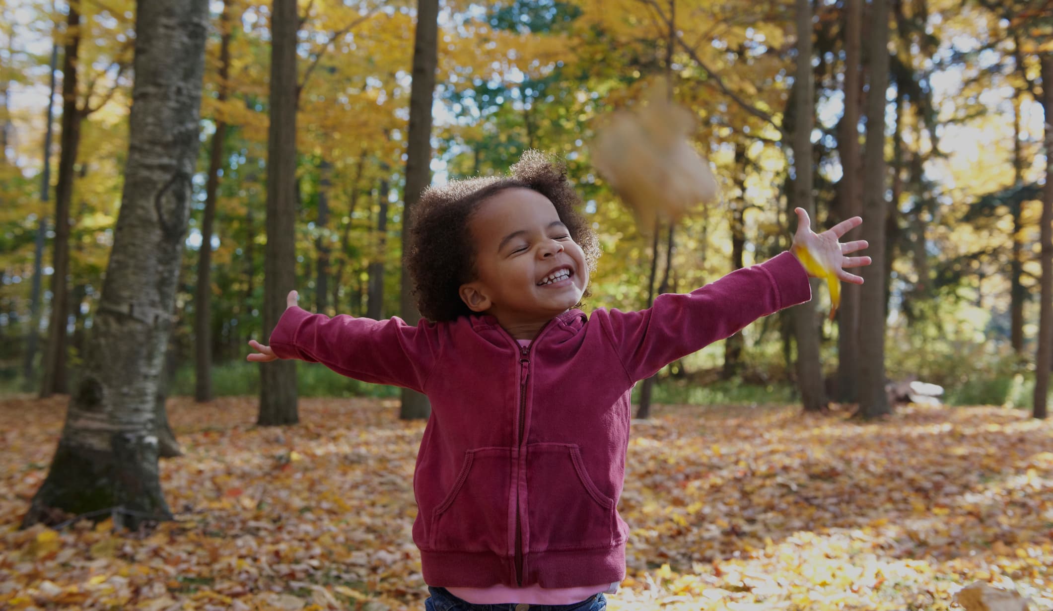 African American girl playing in autumn leaves