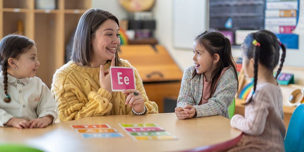 a teacher helps her class learn letters