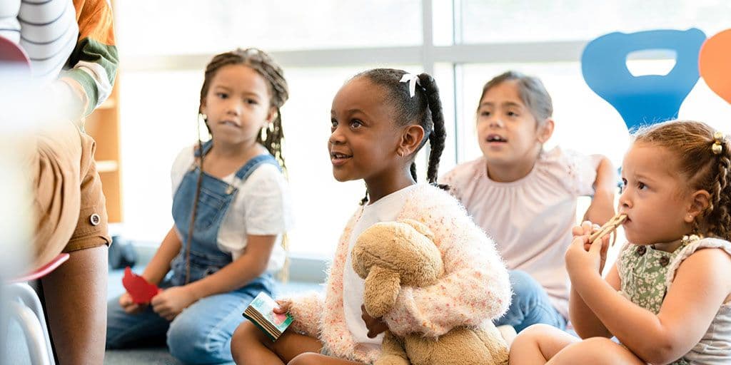 young kids sit on the carpet at daycare