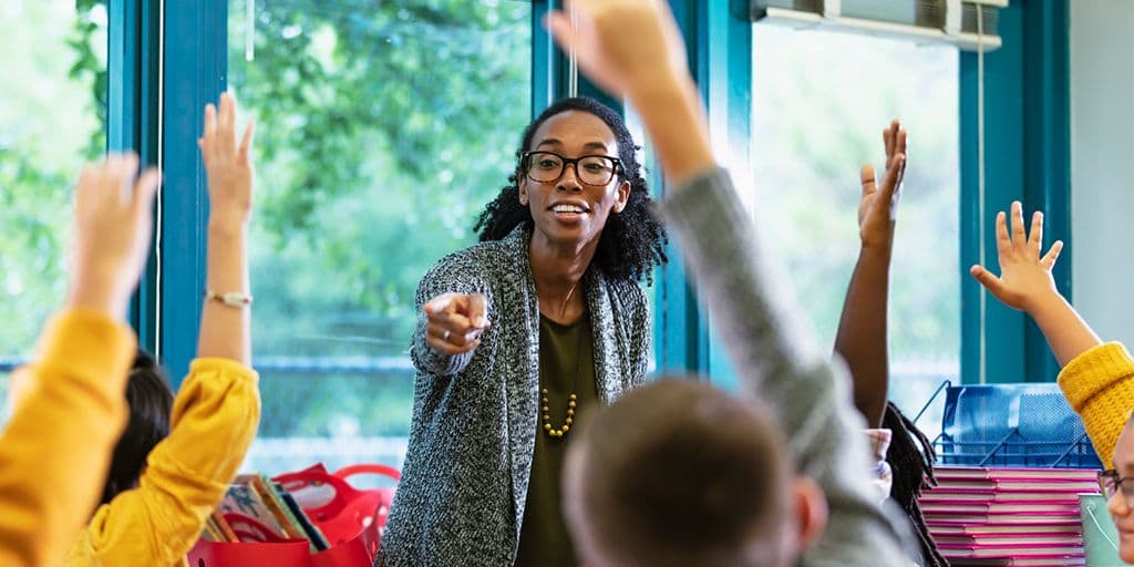 a teacher calls on students raising their hands