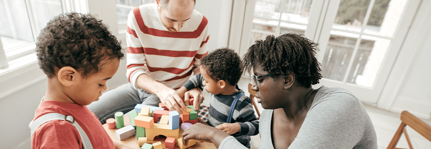 Two adults and young children play with building blocks