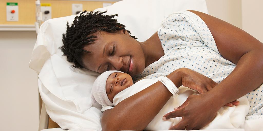 mother in hospital bed holds newborn