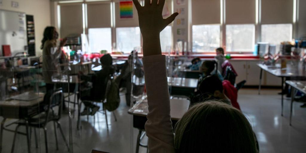 a child raises her hand in class
