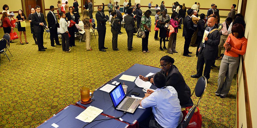 a group of people wait in line for a job fair