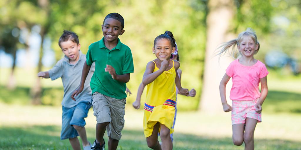 a group of smiling children run towards the camera