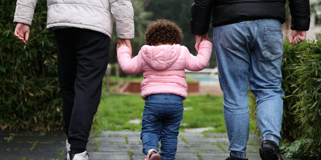 a young girl holds the hands of her parents