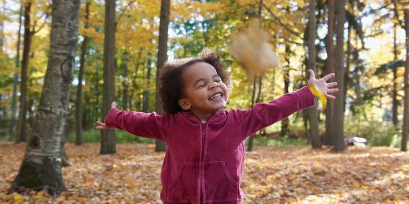 African American girl playing in autumn leaves