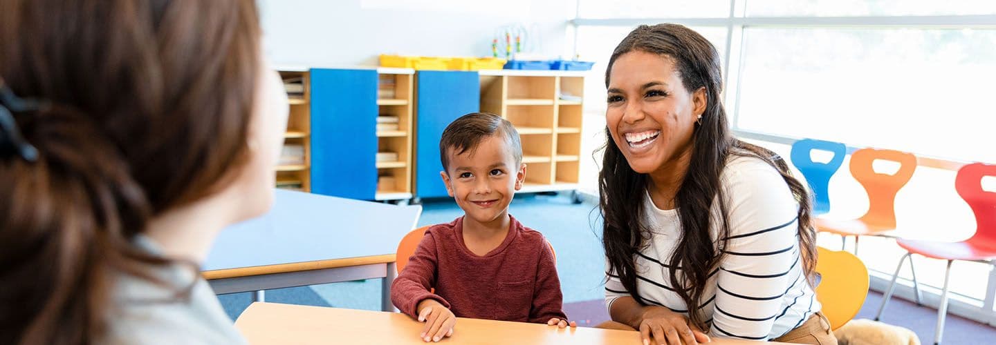 a mother and young child meet with a teacher